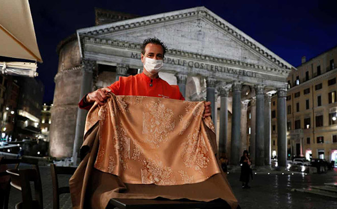 Nhân viên phục vụ bàn đeo khẩu trang dọn dẹp một quán bar trước cửa đền thờ Pantheon nổi tiếng tại Rome (Italia).