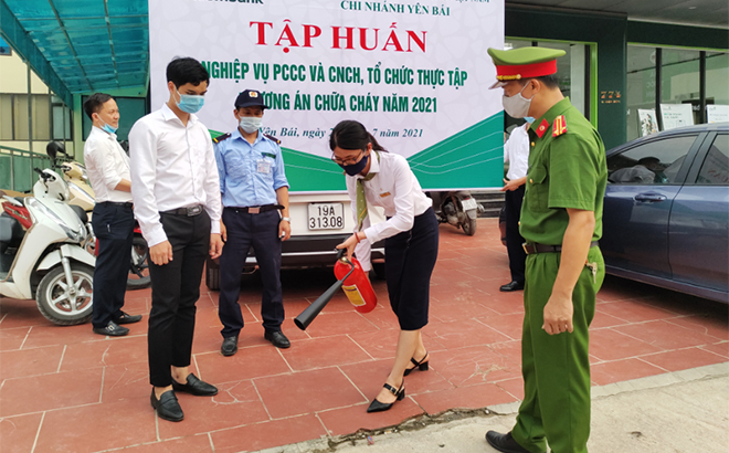 Cán bộ, chiến sĩ Công an tỉnh hướng dẫn nhân viên Chi nhánh Vietcombank Yên Bái thực hành sử dụng bình bọt chữa cháy.