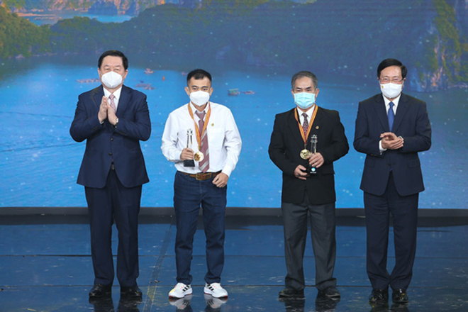 Phó Thủ tướng Thường trực Phạm Bình Minh (bìa phải) và Trưởng Ban Tuyên giáo Trung ương Nguyễn Trọng Nghĩa (bìa trái) cùng trao giải nhất cho hai nhiếp ảnh gia Từ Thế Duy và Lê Châu Đạo.