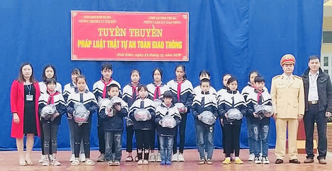 Học sinh Trường Tiểu học và THCS xã Vĩnh Kiên, huyện Yên Bình nhận mũ bảo hiểm.