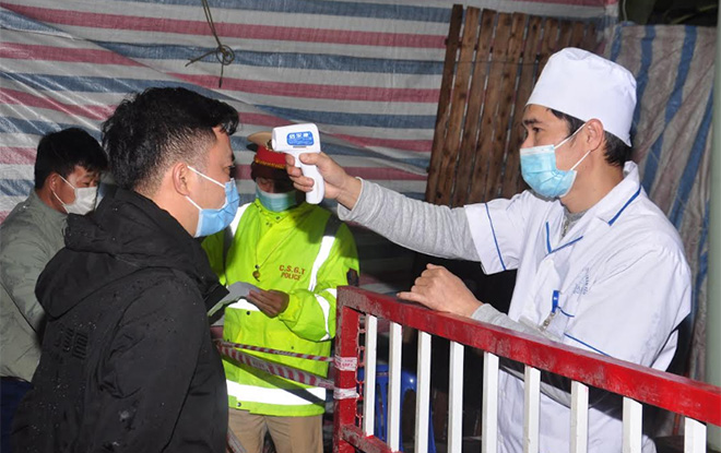 Cán bộ Trung tâm Y tế huyện Trấn Yên đo thân nhiệt cho người dân tại chốt kiểm dịch thôn Linh Đức, xã Minh Quân. (Ảnh: Quyết Thắng)