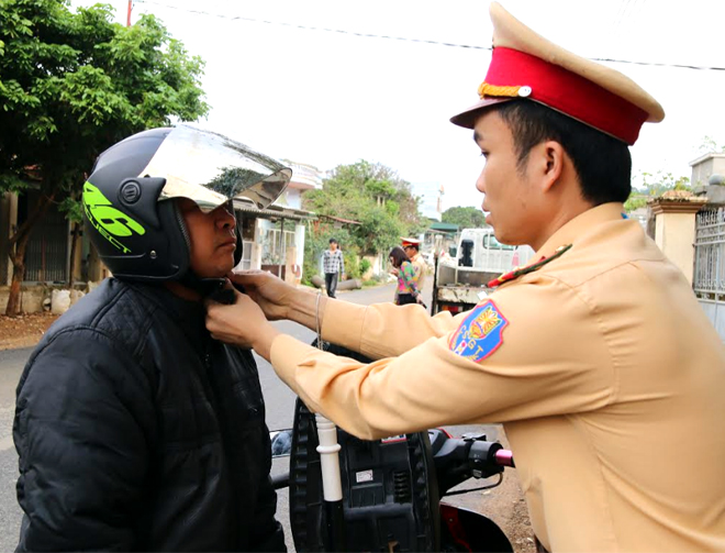 Cảnh sát giao thông huyện Văn Chấn hướng dẫn người dân đội mũ bảo hiểm đúng cách.
