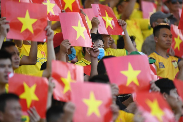 Các cổ động viên, một số người đeo khẩu trang, cầm cờ cổ vũ trước khi bắt đầu trận đấu bóng đá tại tỉnh Hưng Yên ngày 25/5. Các hoạt động thể thao đã trở lại bình thường sau khi Việt Nam nới lỏng các biện pháp hạn chế.