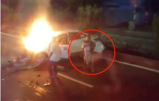 Người dân cứu bé gái (khoanh tròn đỏ) khỏi ô tô bốc cháy (Ảnh cắt từ clip).