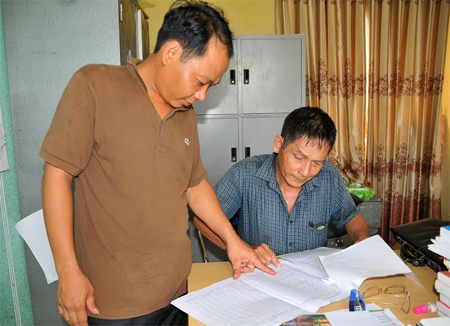 Chủ tịch UBND xã Phúc Lộc - Nguyễn Văn Giáp (người đứng) trao đổi với cán bộ kế toán xã.
